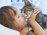 Une enfant embrassant son chat et le serrant contre elle