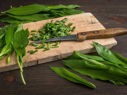 Des feuilles d'ail des ours découpées sur une planche de cuisine