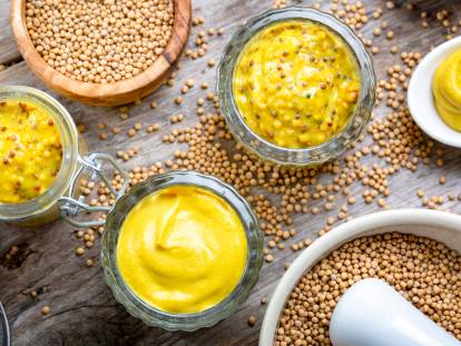 Des pots et graines de moutarde sur une table rustique