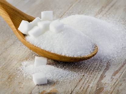 Du sucre blanc dans une cuillère en bois