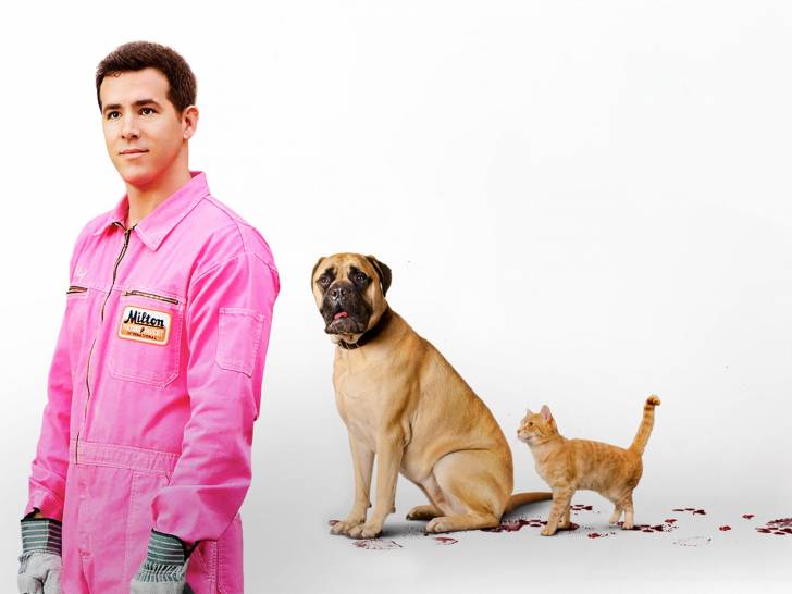 Sur un fond blanc, Ryan Reynolds debout à côté du chien et du chat acteurs du film «The Voices», parmi des empreintes de pattes rouges