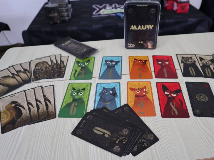 La boîte du jeu «Mauw» et ses cartes posées sur une table