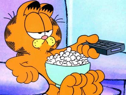 Garfiel, un chat roux assis sur un fauteuil, tenant la télécommande dans une patte dans « Garfield »