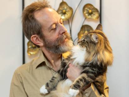 Frédéric Richard, fondateur de l'élevage La Natte à Chats, portant et regardant dans les yeux un chat