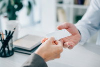 Un ostéopathe donnant sa carte de visite à sa cliente