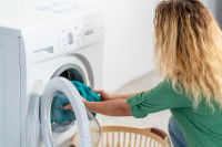 Une femme met son linge dans la machine
