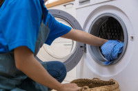 Une femme met du linge dans la machine à laver
