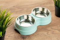 Une gamelle double posée sur un sol de bois