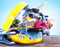 Une valise jaune remplie à craquer de vêtements et d'accessoires