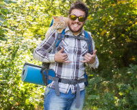 Un homme fait de la randonnée avec son chat sur son sac à dos