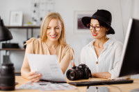 Une photographe et sa cliente, assises côte à côte et regardant une feuille de papier