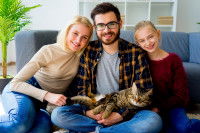 Une famille assise sur le canapé, posant avec leur chat