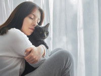 Une femme serrant dans ses bras un chat gris