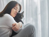 Une femme serrant dans ses bras un chat gris