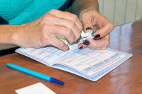 Un vétérinaire en train de remplir le carnet de santé d'un chat en y collant une étiquette de vaccin.