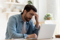 Un homme embêté regarde son ordinateur portable