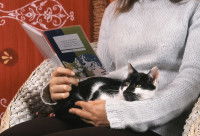 Une femme avec son chat sur les genoux, tient un carnet de vaccination