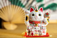 Vue proche d'une statuette de Maneki Neko avec un éventail en arrière-plan