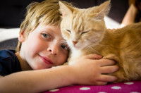 Un jeune garçon se tient à côté de son chat