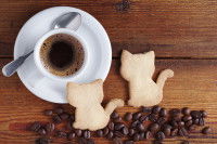 Une tasse de café avec des biscuits en forme de chat