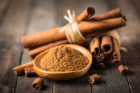 De la cannelle en poudre et en bâtonnet sur une table de bois