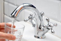 Une femme remplit un verre avec de l'eau du robinet