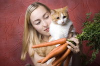 Une maitresse tenant son chat et une botte de carottes dans ses mains