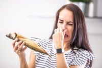 Une femme se bouche le nez devant un poisson pourri