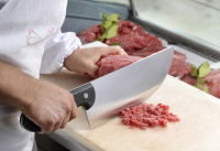 Un cuisinier découpe de la viande en petits morceaux