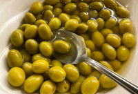 Un bol contenant des olives entières et une cuillère