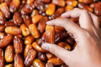 Une femme tient une datte entre ses doigts