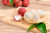 Des litchis décortiqués dans un petit bol sur une planche de bois