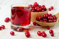 Un verre de jus de cranberry avec des canneberges dans des cuillères en bois