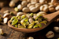 Une cuillère en bois contenant des pistaches décortiquées