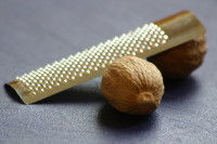 Des noix de muscade à côté d'une râpe