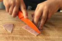 Un homme coupe du jambon blanc en petits morceaux