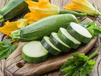 Des courgettes entières et en rondelles sur une planche de bois