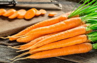 Des carottes entières et en rondelles sur une table en bois