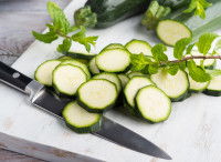Des courgettes découpées en rondelles sur une planche de cuisine