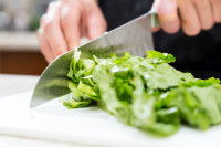 Une femme découpe de la salade avec un couteau