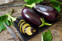 Des aubergines sur une planche de cuisine à côté d'un couteau