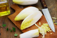 Une endive coupée en morceaux avec un couteau et une planche