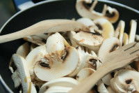 Des champignons coupés en train de cuire dans une poêle
