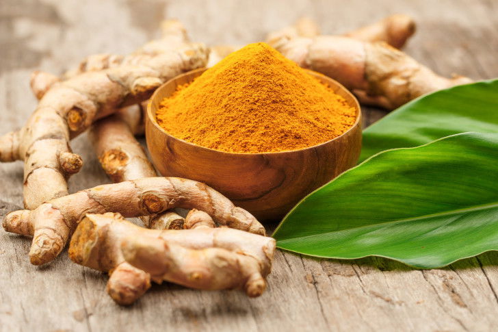 Du curcuma frais et en poudre sur une table en bois