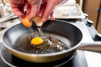 Une femme fait cuire un oeuf à la poêle