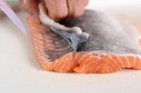 Un homme découpe la peau du saumon avec un couteau
