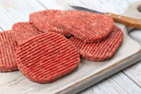 Une pile de steaks hachés sur une planche de cuisine