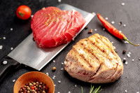 Un steak de thon cru et un steak de thon cuit sur un fond noir