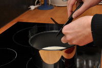 Un homme coupe une gousse de vanille dans une casserole