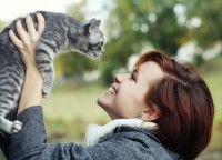 Une femme heureuse tient un chaton au-dessus de sa tête